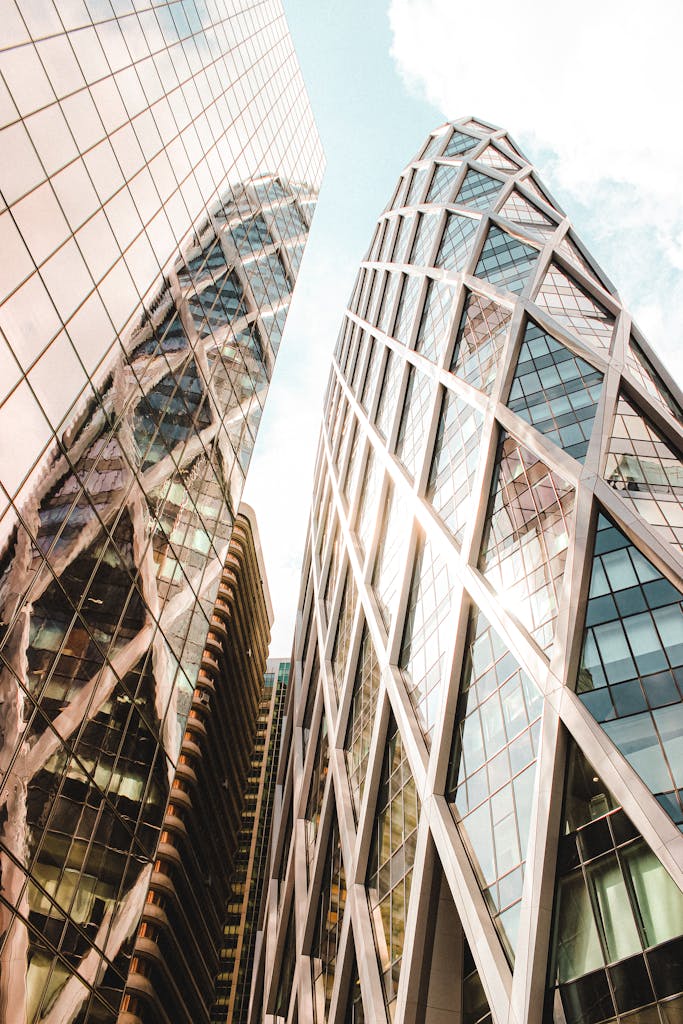 From below of contemporary towers with shiny reflecting glass facades located in city district